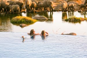 Infinity Pool next to Elephant Water Hold Two Women enjoy