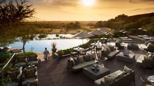 Waiter walks with drinks at sunset at Four Seasons Safari Pool 