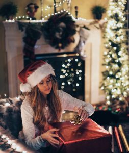 Woman Opening A Christmas Present With LIghts in Background