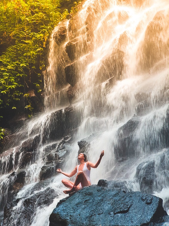 woman meditating at a waterfall